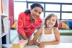 Portrait of teacher with girl in school library