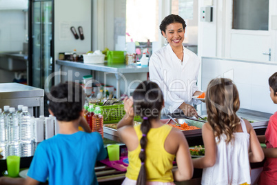 Woman serving food to schoolchildren