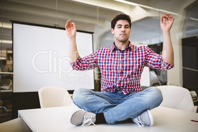 Businessman performing yoga in meeting room
