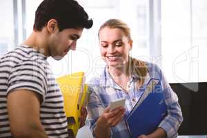 Executives with documents using cellphone at creative office