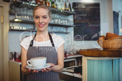 Portrait of happy waitress serving beverage at cafe