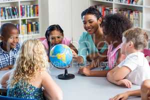 Female teacher teaching children using globe