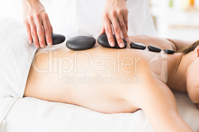 Masseur giving hot stone massage to woman