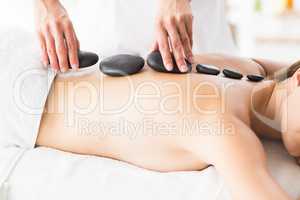 Masseur giving hot stone massage to woman