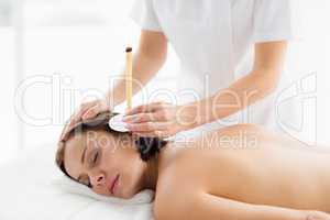 Woman receiving ear candle treatment from masseur