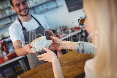 Tilt shot of barista serving coffee to woman at cafe