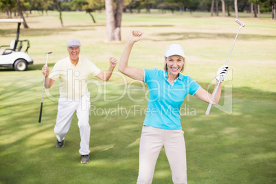 Golfer couple celebrating success while standing on field