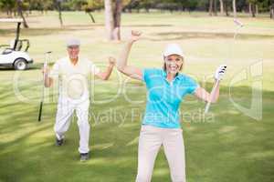 Golfer couple celebrating success while standing on field