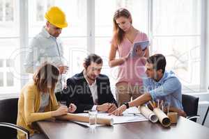 Interior designer with coworkers discussing blueprint
