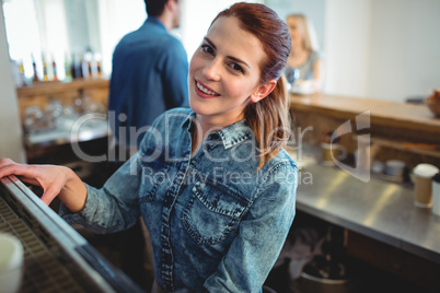 Portrait of happy barista with colleague and customer at cafe