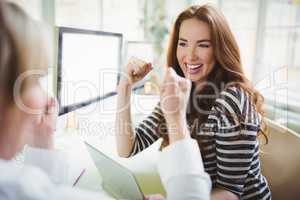 Businesswoman punching in air while discussing with colleague in