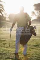 Full length Rear view of man carrying golf bag