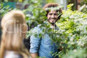 Male gardener looking at woman standing by plants