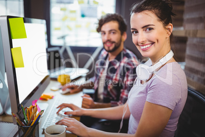 Businesswoman working with male colleague at computer desk