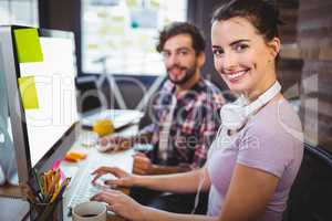 Businesswoman working with male colleague at computer desk