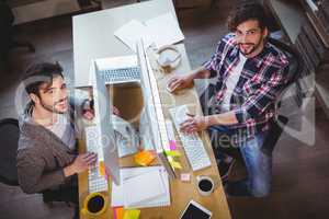 Happy male colleagues working at computer desk