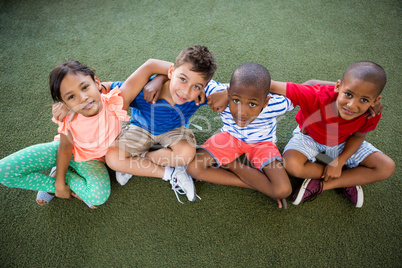 High angle portrait of happy children sitting on grass