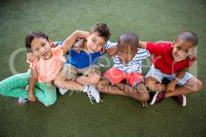 High angle portrait of happy children sitting on grass