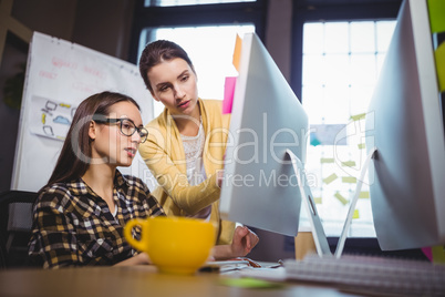 Female colleagues discussing over computer