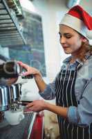 Waitress wearing Santa hat using espresso maker at cafe
