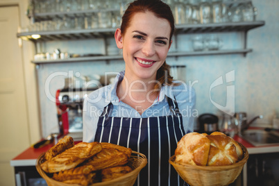 Portrait of happy barista offering breads at cafe