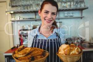Portrait of happy barista offering breads at cafe