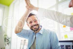 Smiling coworkers giving high-five in creative office