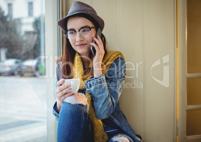 Happy woman talking on mobile phone at cafe