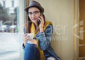 Happy woman talking on mobile phone at cafe