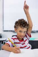 Elementary boy raising hand in classroom