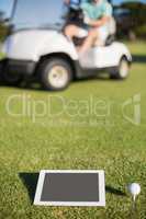 Golf ball on tee by digital tablet