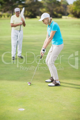 Woman playing golf while standing by man