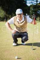 Portrait of golfer crouching and looking his ball