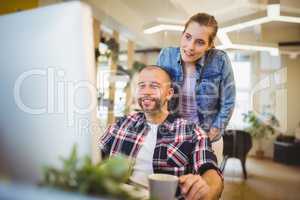 Businessman looking at computer while working with colleague