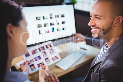 Photo editors smiling while discussing over computer