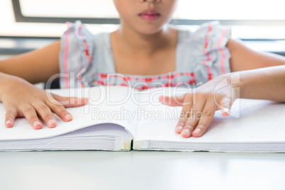 Midsection of blind girl reading braille book