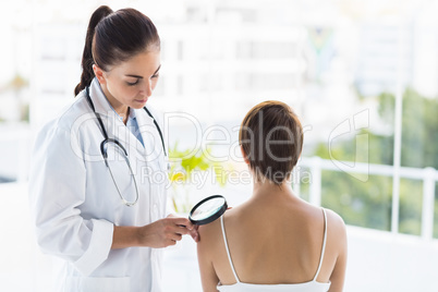 Doctor examining patient with magnifying glass