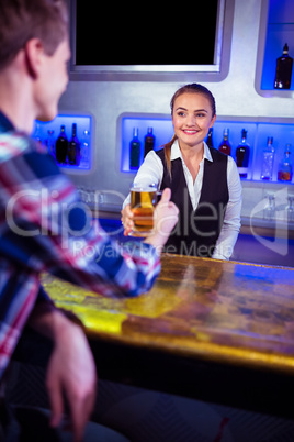 Smiling bartender serving beer to man