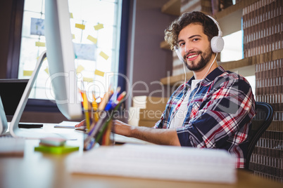 Creative businessman using computer while listening music