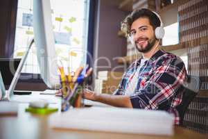 Creative businessman using computer while listening music