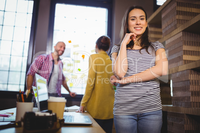 Confident businesswoman with coworkers in background Confident businesswoman with coworkers in background