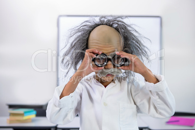 Boy dressed as scientist holding eyeglasses in classroom