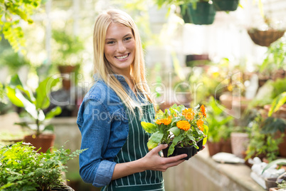 Happy beautiful gardener holding potted flowers