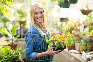 Happy beautiful gardener holding potted flowers