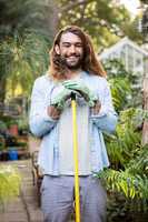 Portrait of happy gardener with long hair holding tool at garden