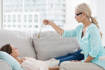 Hypnotherapist holding pendulum by patient