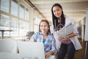 Portrait of female colleagues working on laptop in office