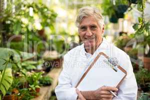 Male scientist holding clipboard at greenhouse