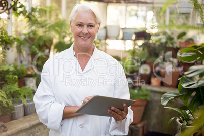 Mature female scientist smiling while using digital tablet