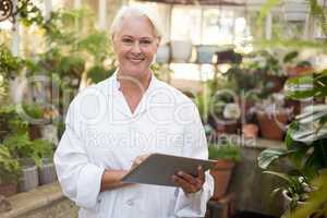 Mature female scientist smiling while using digital tablet